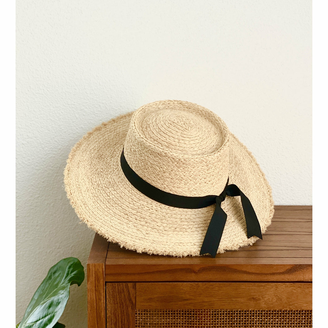 round top straw hat with black ribbon fringed edges